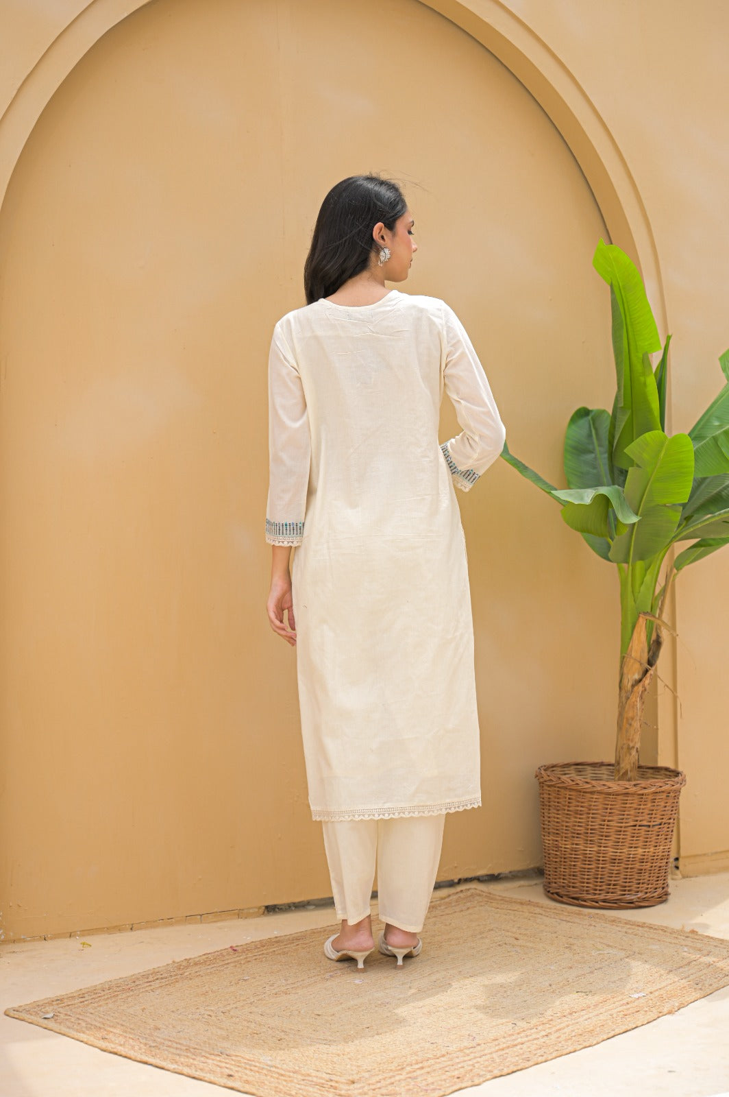 Rear view of woman wearing cream embroidered suit set with long sleeves and matching pants