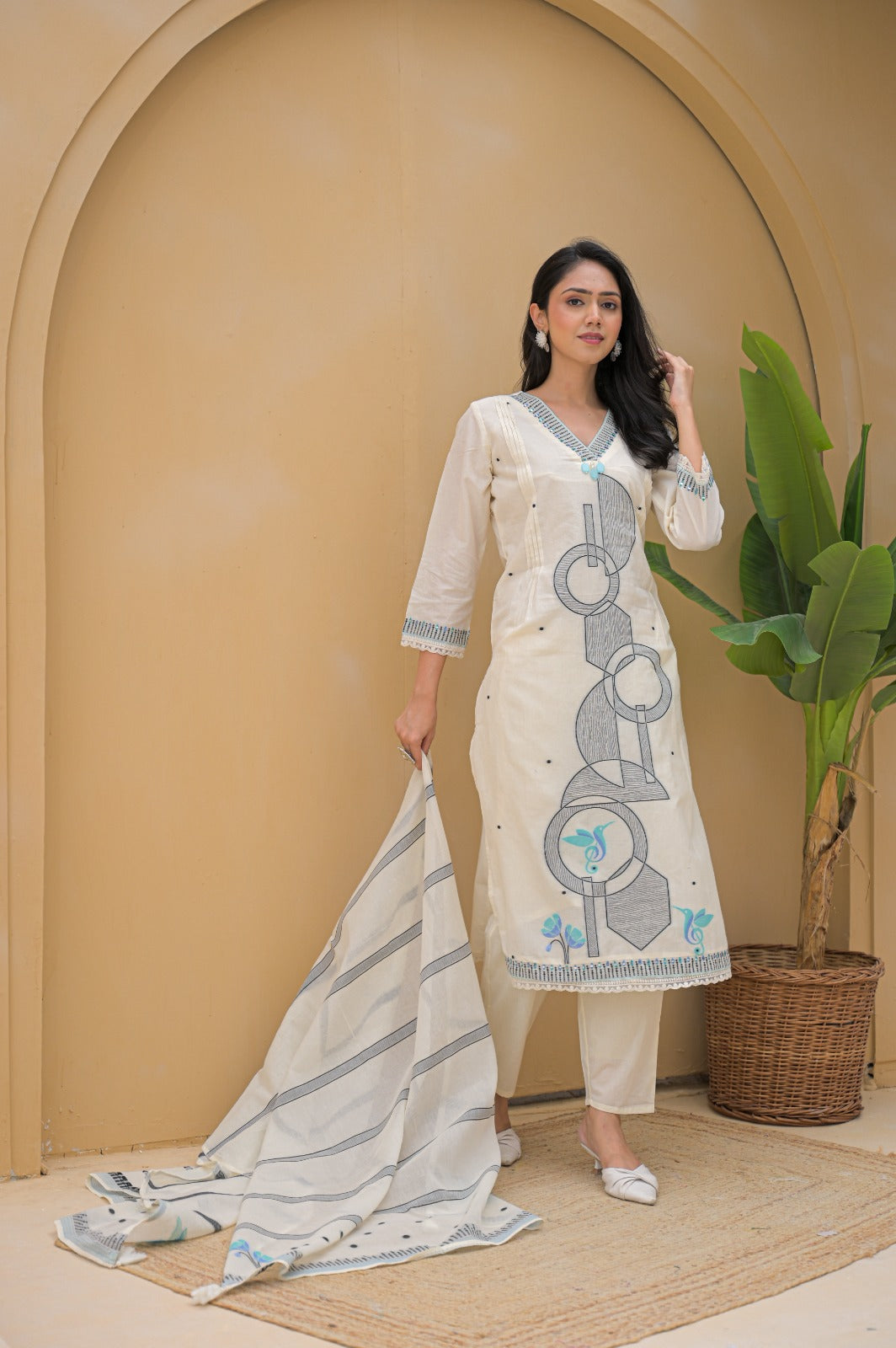 Woman wearing cream embroidered suit set with geometric and floral embroidery standing indoors