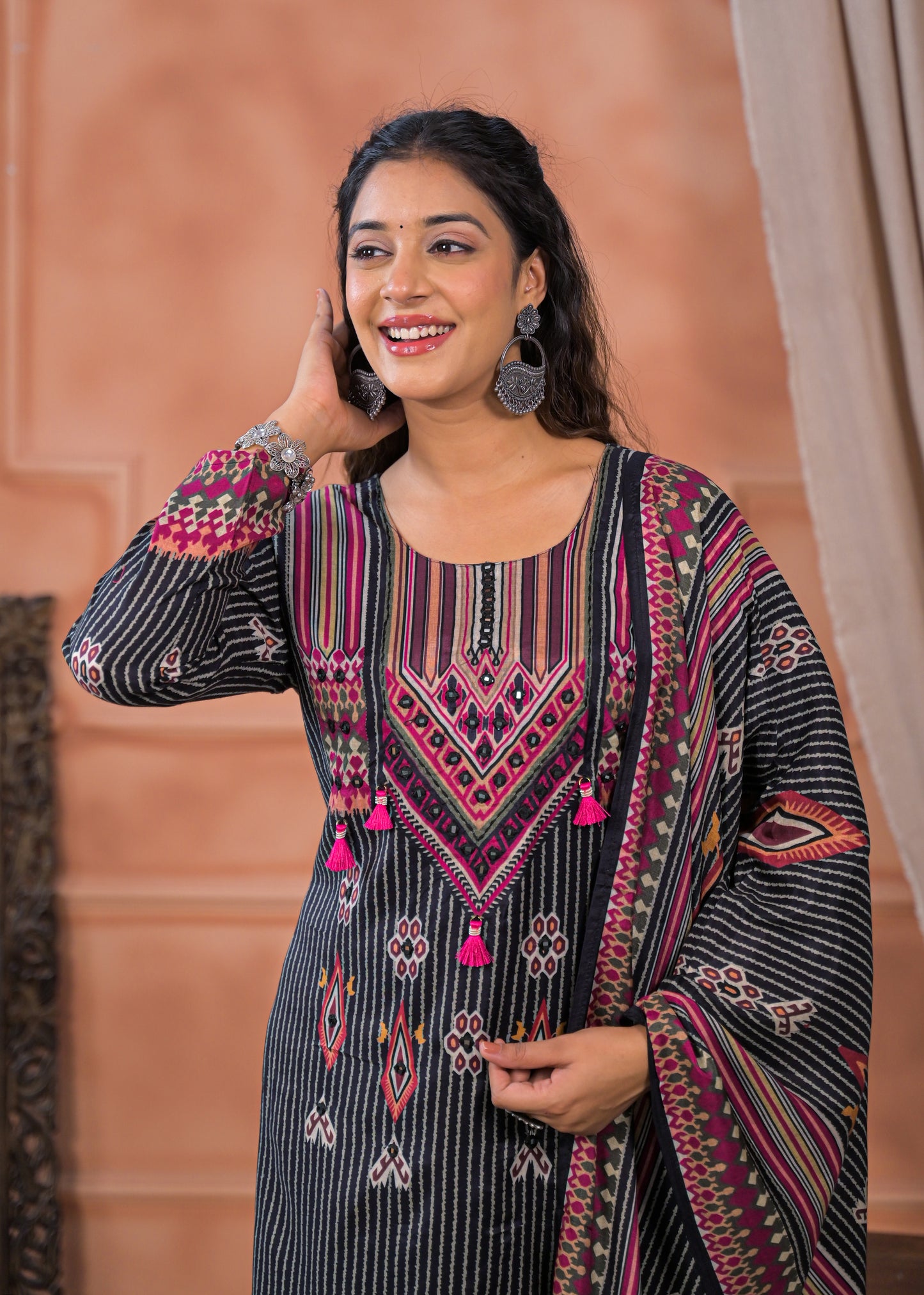 Woman wearing a black striped embroidered suit set with pink and white detailed embroidery and matching dupatta