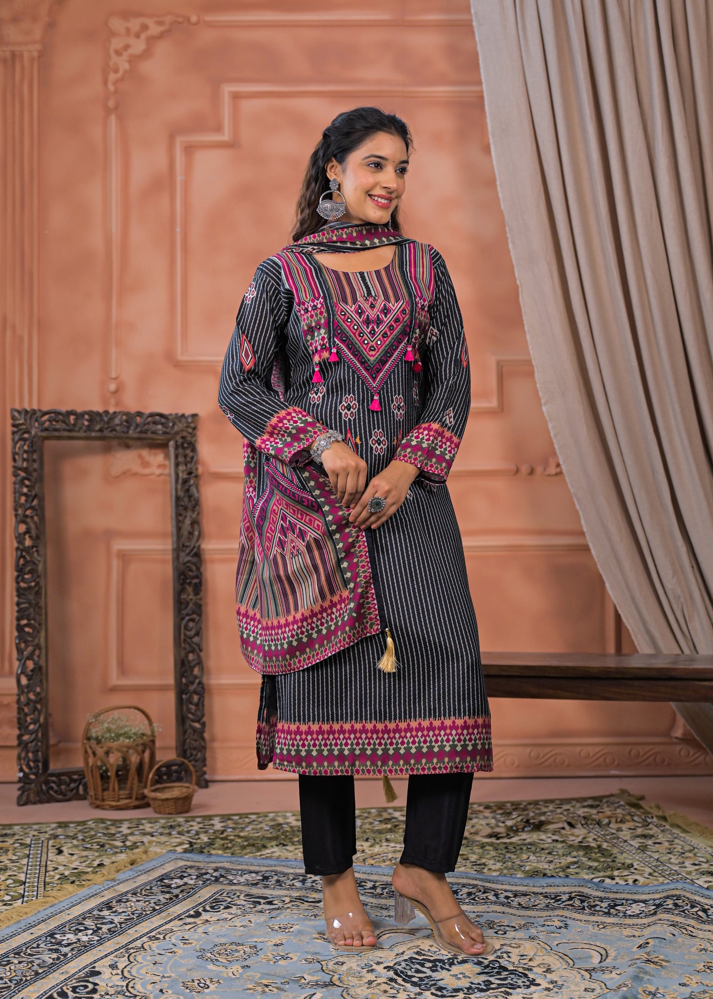 Model wearing a black striped embroidered suit set with pink detailing and matching dupatta