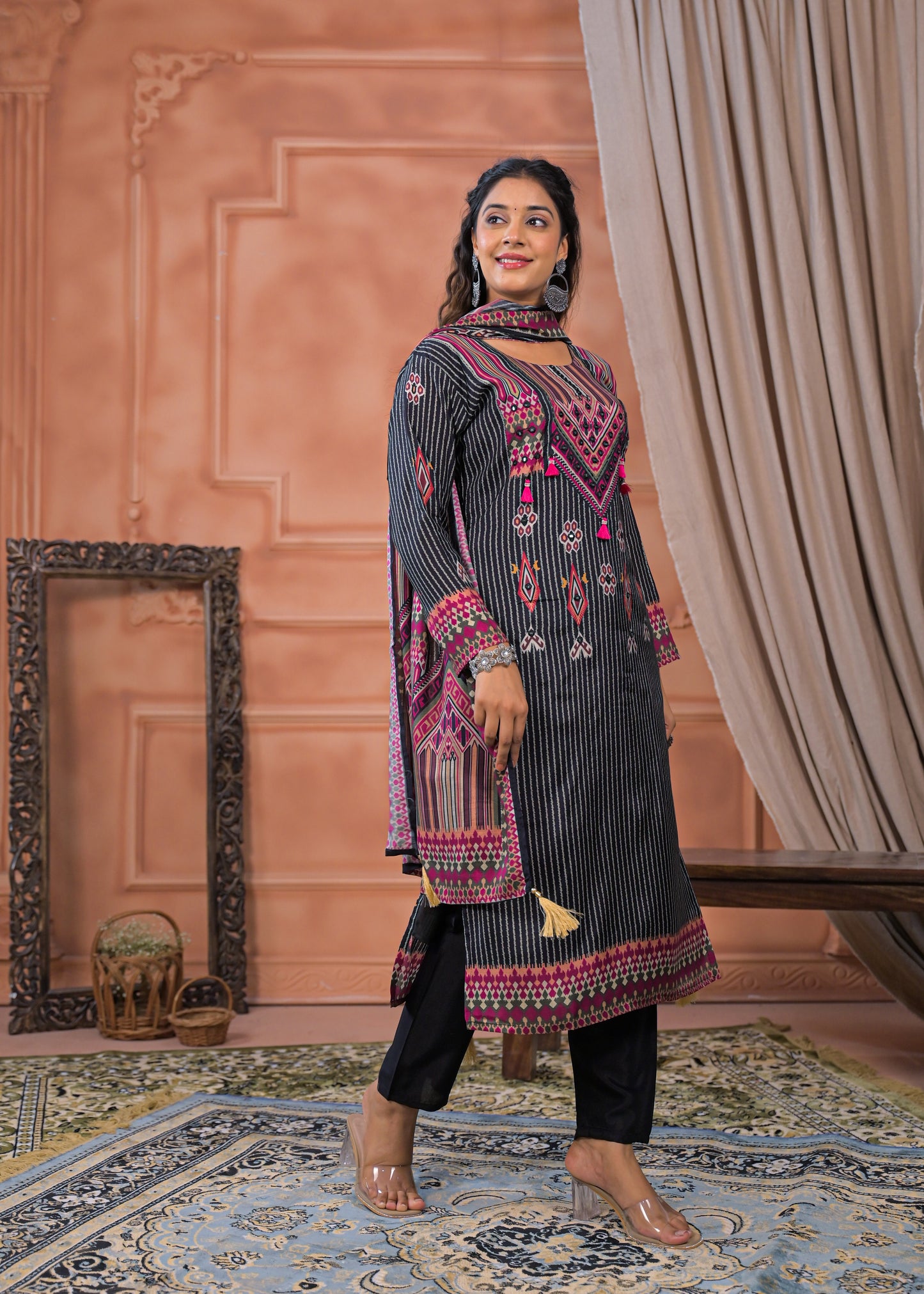 Woman wearing black striped embroidered suit set with pink and red detailed embroidery from Dharini's Store