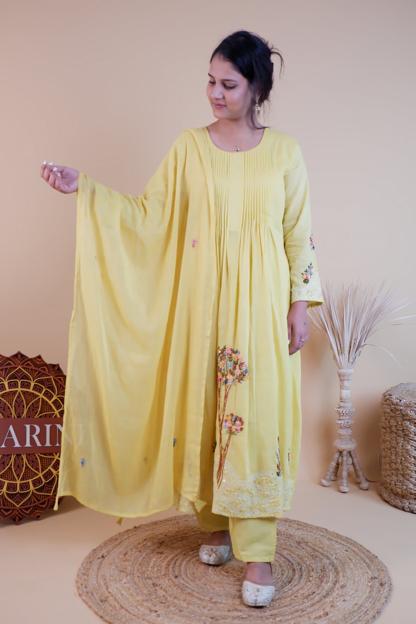 Woman wearing yellow embroidered cotton dress with floral designs and flowing sleeves at Dharini's Store