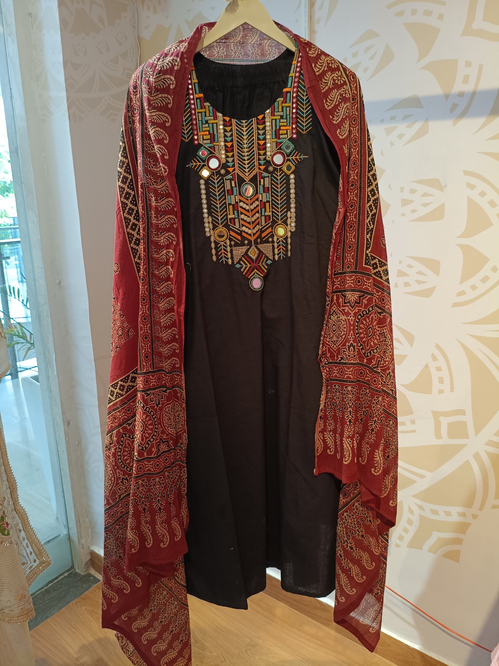 Black cotton festive suit with colorful embroidered neckline and red patterned dupatta from Dharini's Store
