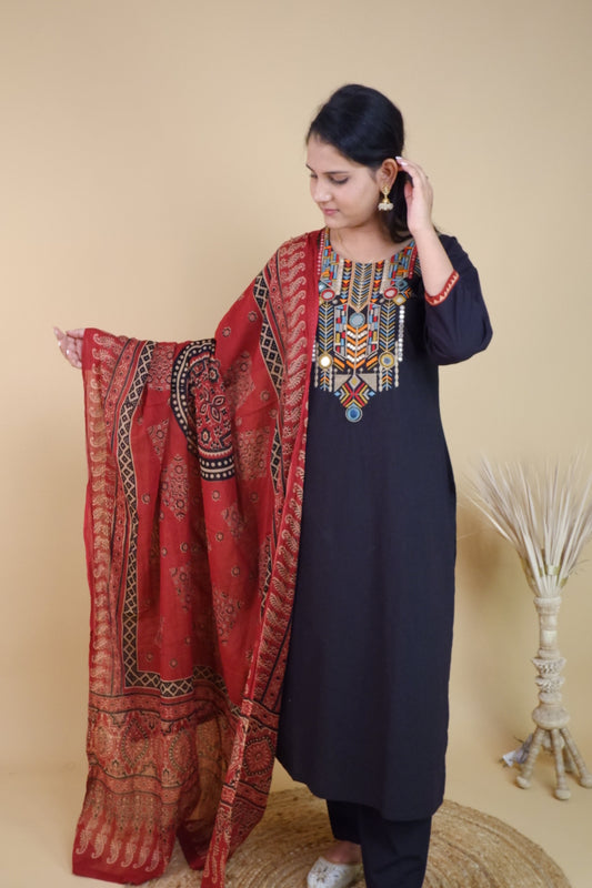 Woman wearing black cotton festive suit with colorful embroidered neckline and red patterned dupatta