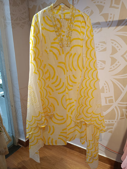 Cream and yellow cotton suit for women hanging on wooden hanger with intricate yellow patterns