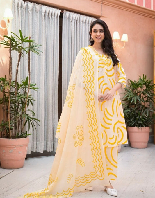 Woman wearing cream and yellow cotton suit for women with floral and wave patterns standing indoors