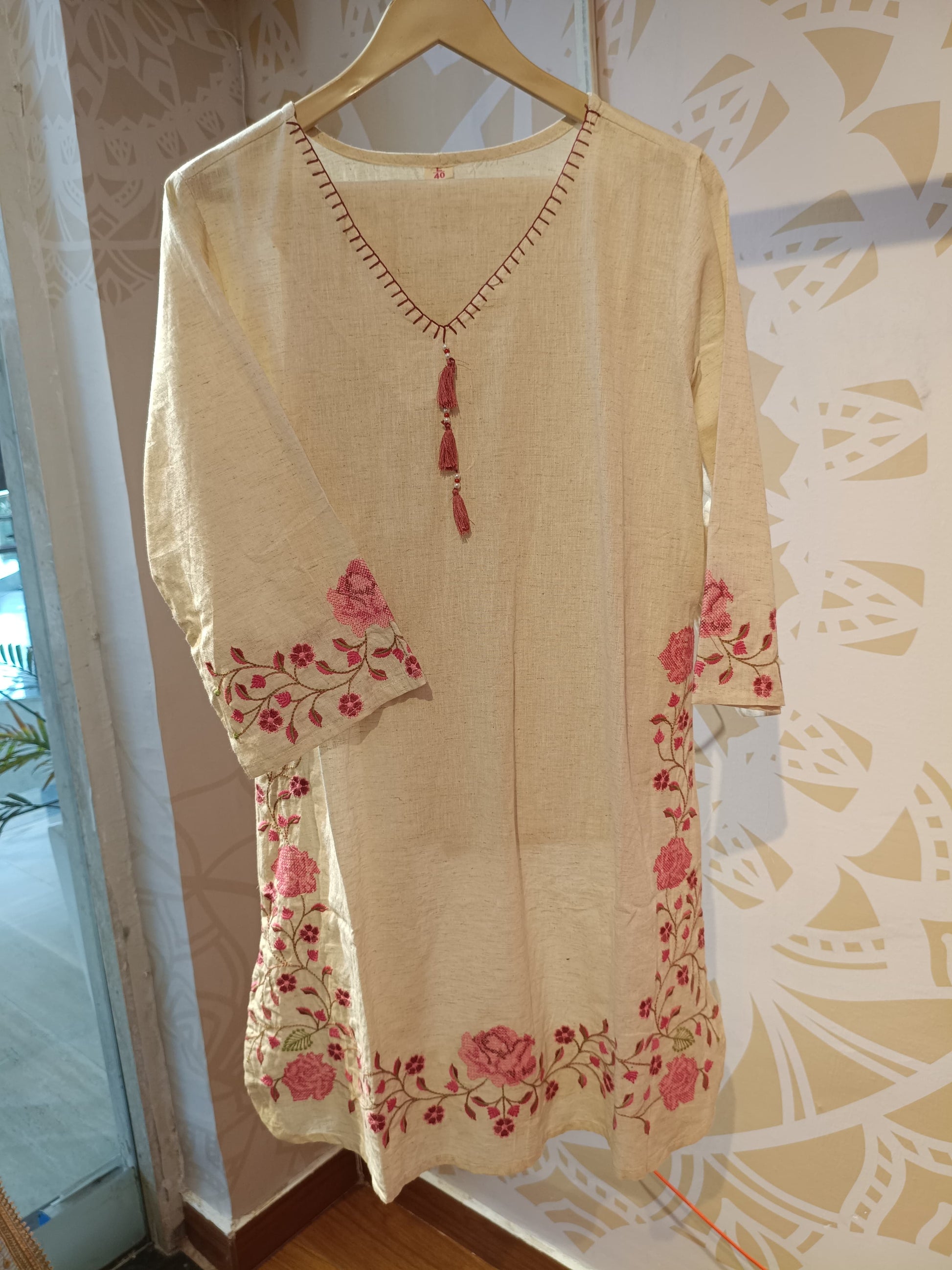 Embroidered khadi cotton kurti in beige with pink floral designs and tassels on the neckline