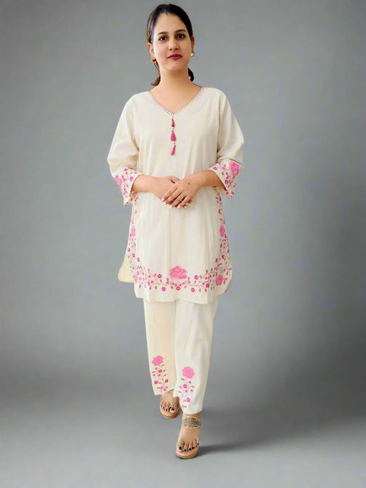 Woman wearing white embroidered khadi cotton kurti with pink floral designs walking indoors