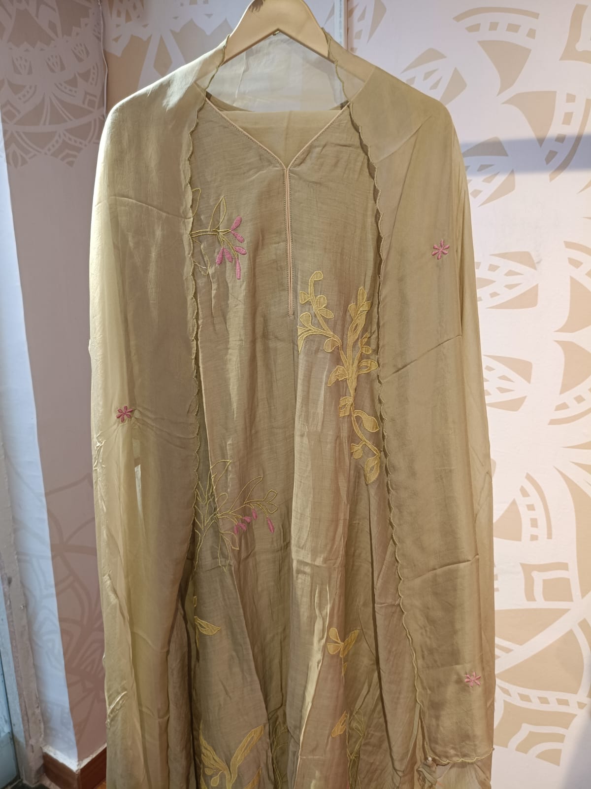 Olive chanderi embroidered suit with delicate floral embroidery hanging on wooden hanger