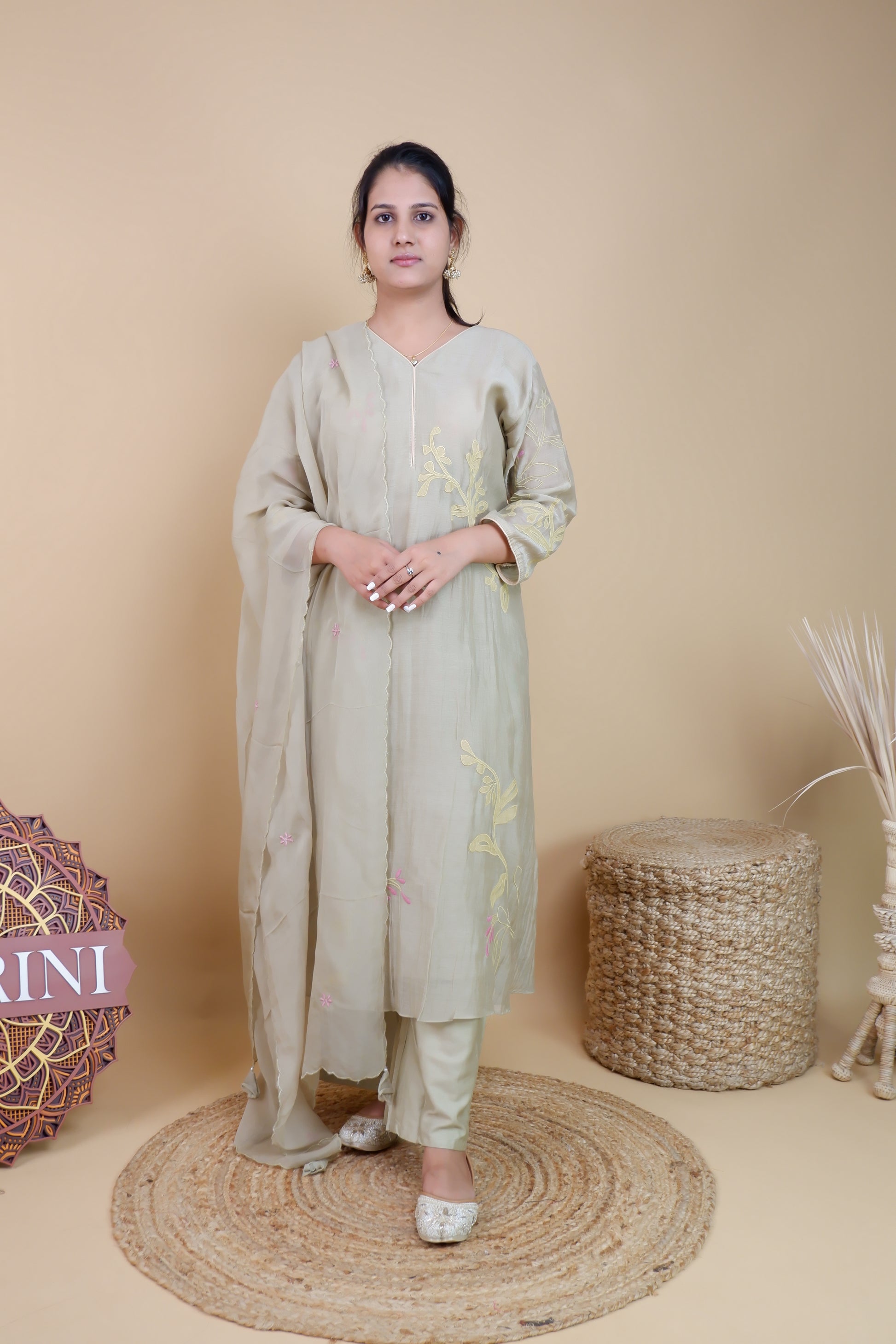 Woman wearing olive chanderi embroidered suit with matching dupatta and pants in neutral studio setting