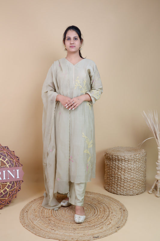 Woman wearing olive chanderi embroidered suit with matching dupatta and pants in neutral studio setting