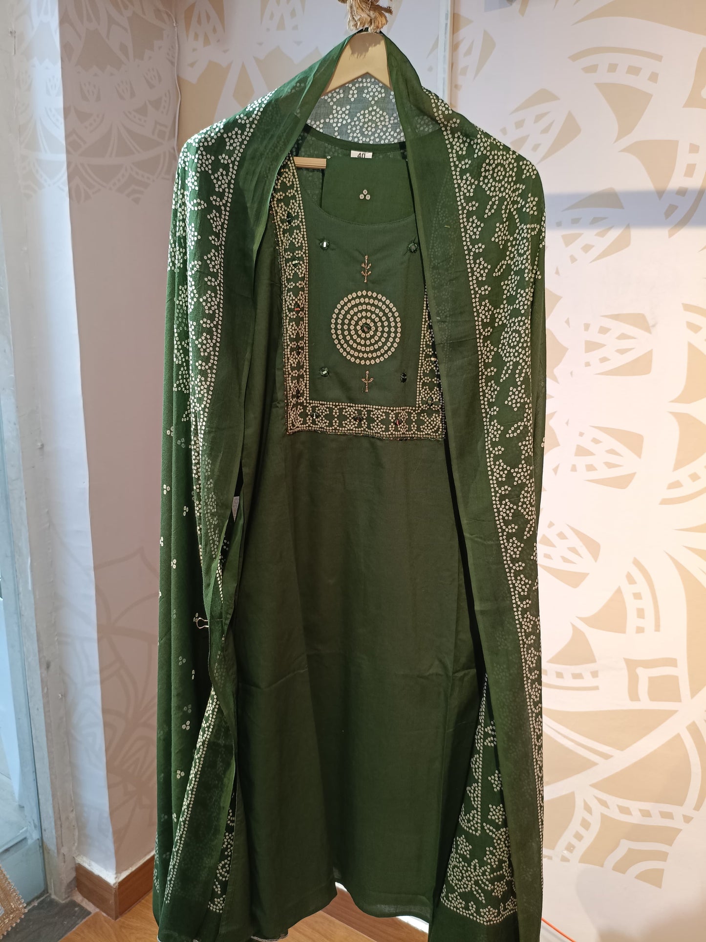 Olive green cotton suit for women displayed on a hanger with intricate white embroidery details