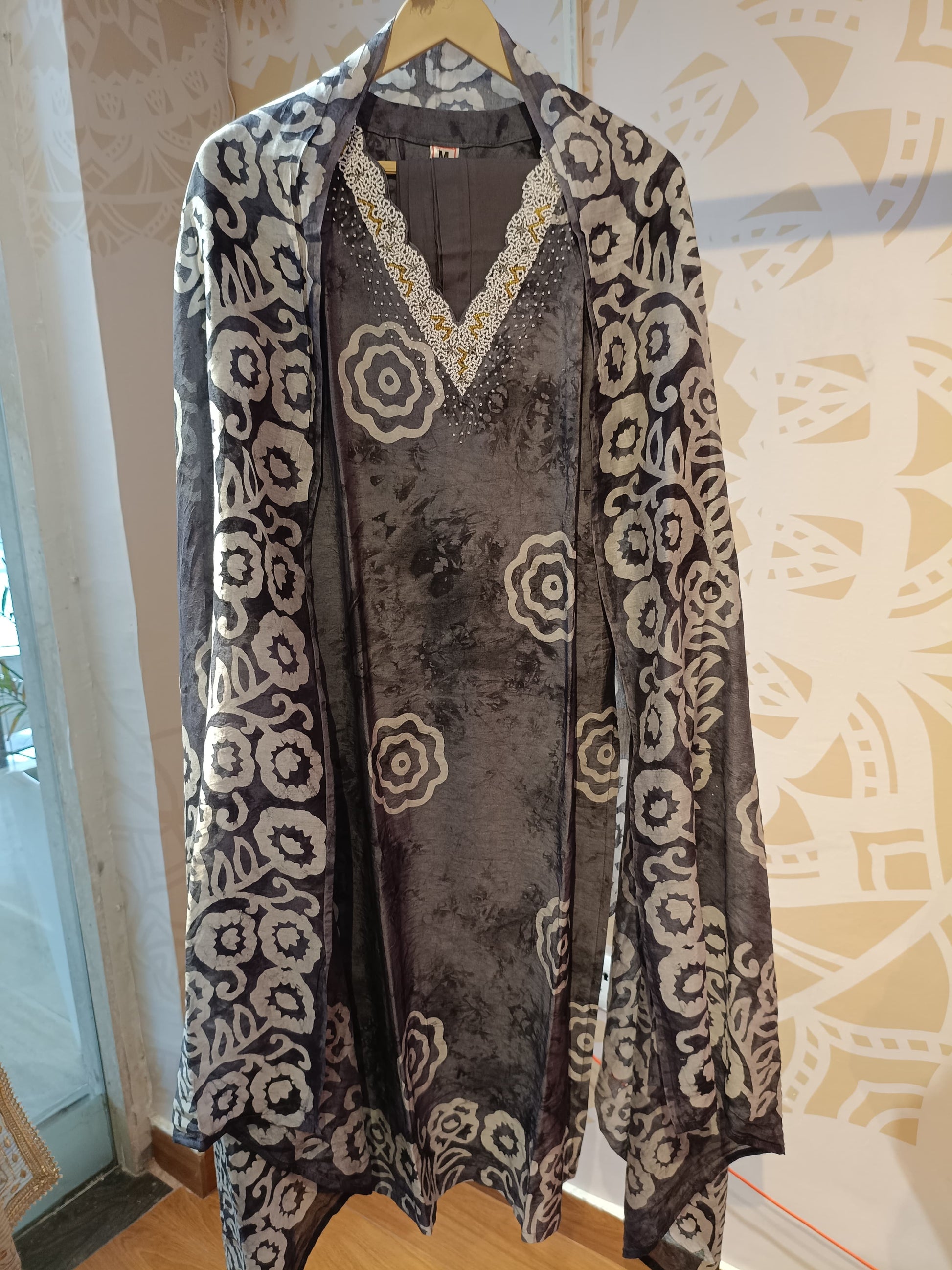 Grey and white cotton suit set with floral print and lace neckline from Dharini's Store hanging on a hanger