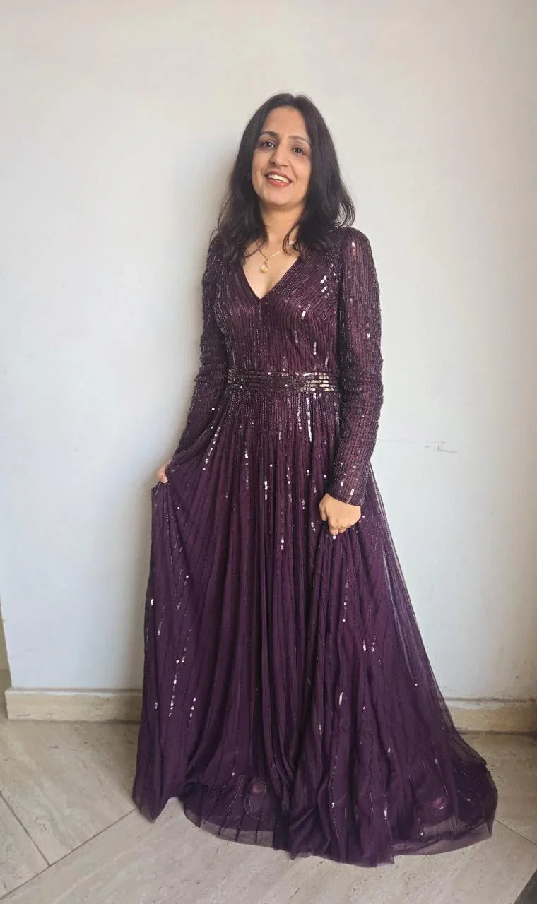 Woman wearing a purple sequin women's partywear gown with long sleeves and V-neck