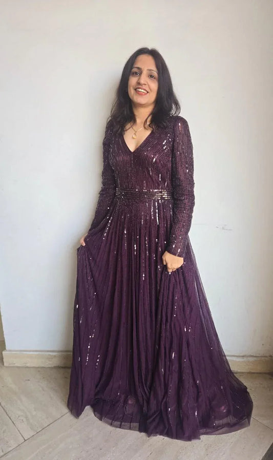 Woman wearing a purple sequin women's partywear gown with long sleeves and V-neck