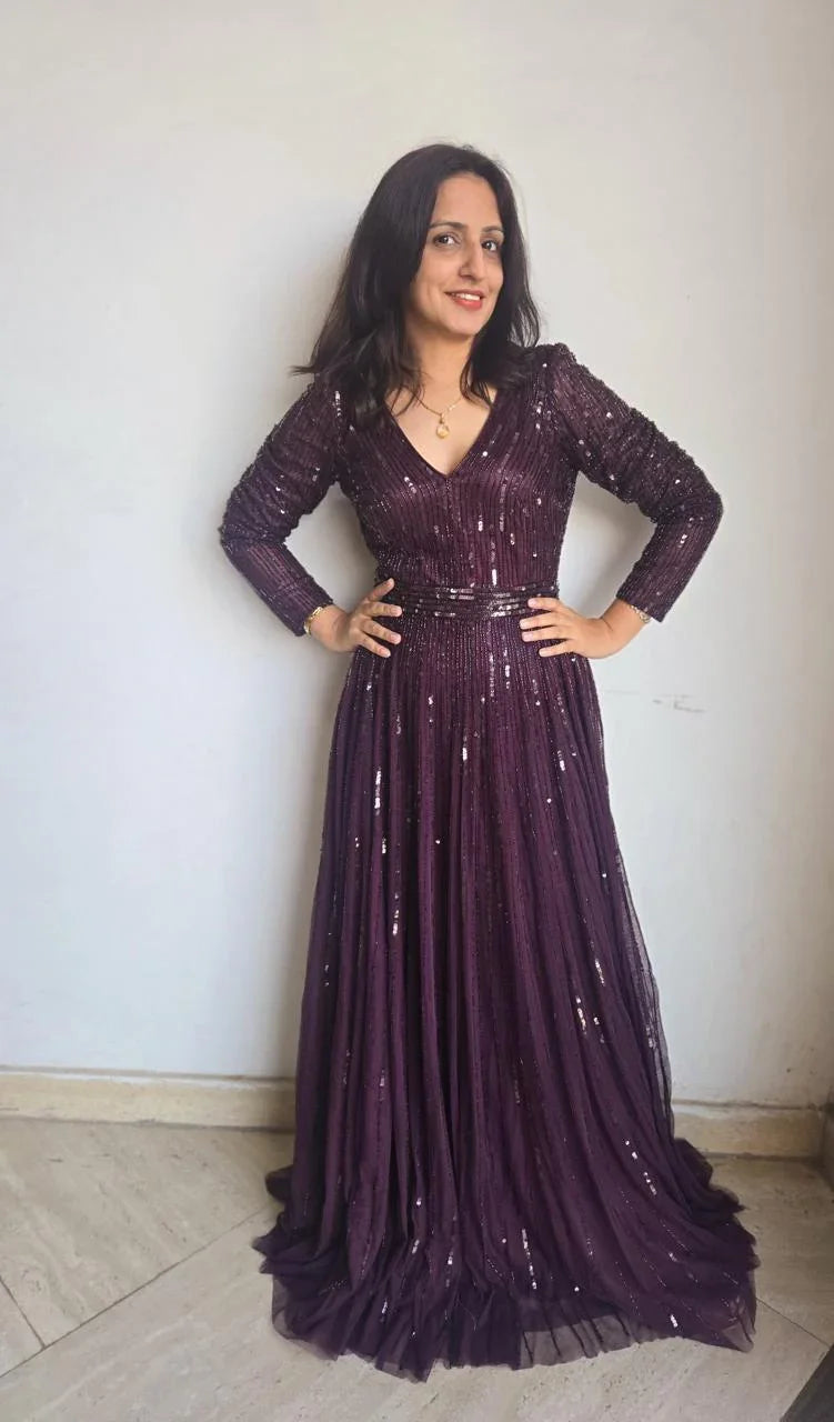 Woman wearing a purple sequined women's partywear gown with long sleeves and a fitted waist