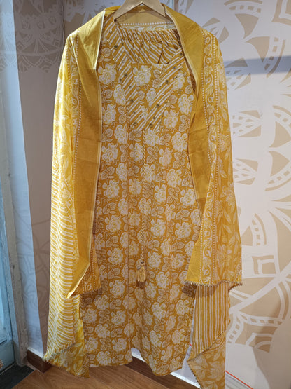 Yellow floral cotton suit with detailed floral and striped patterns hanging on a wooden hanger