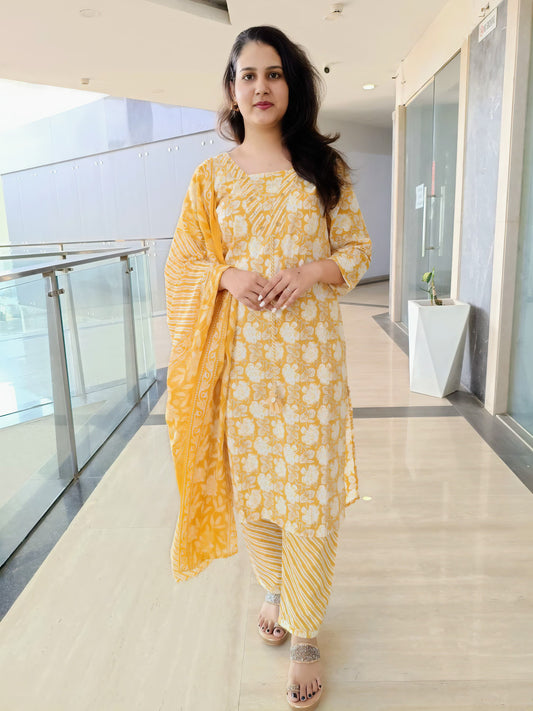 Woman wearing yellow floral cotton suit with matching dupatta and striped pants indoors