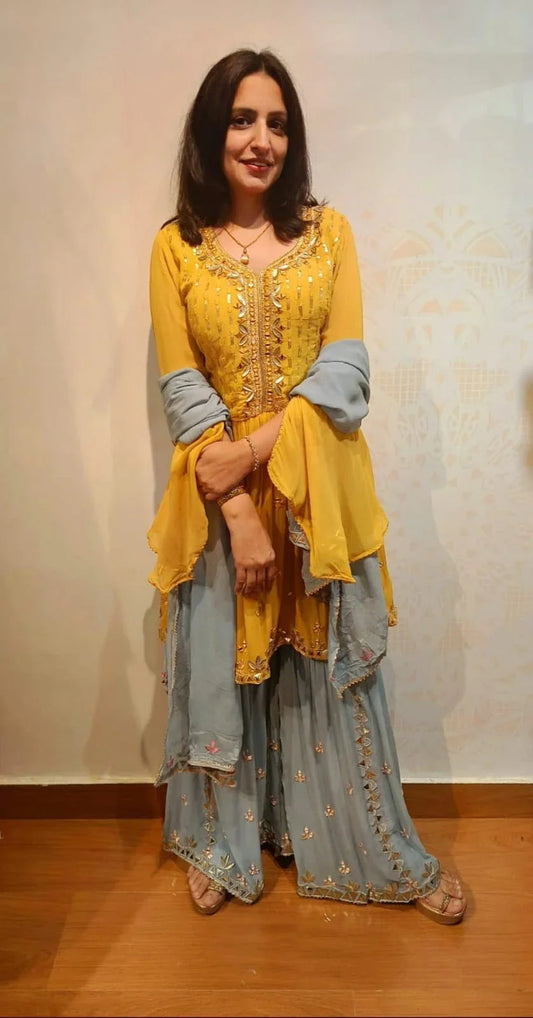 Woman wearing yellow grey georgette gottapatti dress with intricate embroidery and flared sleeves